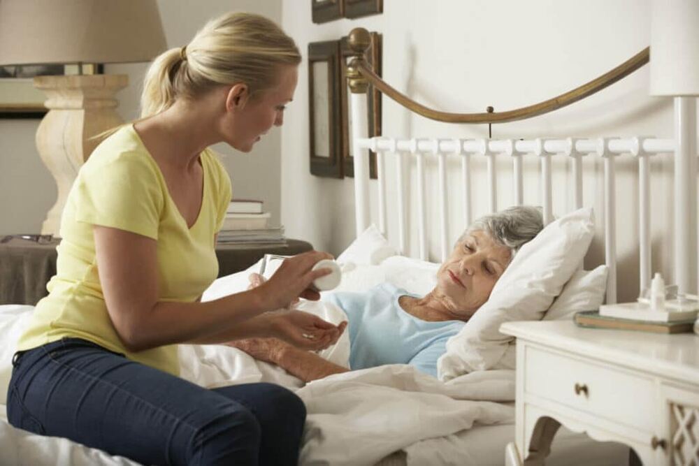 A carer helping an older lady with her medicines at home